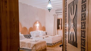 Ein Hotelzimmer mit zwei Betten, einem gemusterten Boden, einer Zierwand und einer hängenden Leuchte.