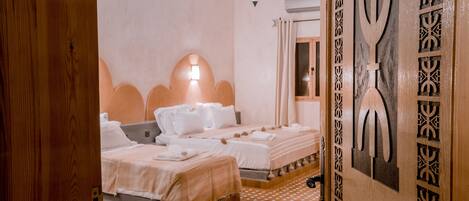 Una habitación de hotel con dos camas, piso estampado, pared decorativa e iluminación colgante.