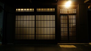 Une entrée sombre, dotée de lambris verticaux et d’une enseigne lumineuse au-dessus.