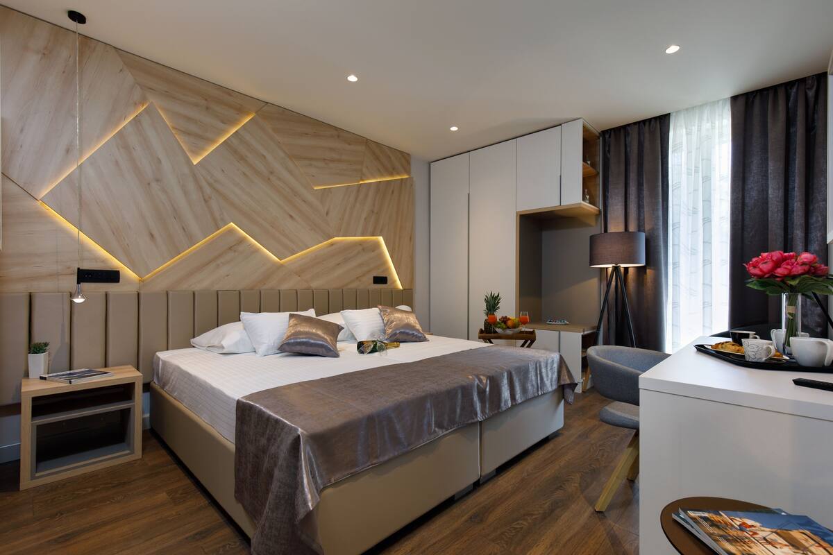 A modern hotel room with a large bed, bedside tables, a desk, and a chair.