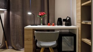 A modern room with a desk, a chair, a small TV, a lamp, a vase with flowers, and a coffee maker. - Sailor Boutique Rooms (Split)