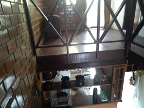 A kitchen with brick walls, a wooden countertop, and various kitchen appliances. - Chalé Mont Blanc (Gravata)
