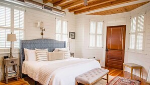 A bedroom with a large bed, a wooden bench, a bedside table, and a red patterned rug.