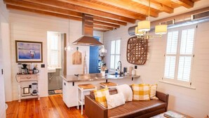 A cozy living room with a brown leather sofa, a coffee table, and a kitchen area with a stove and sink.