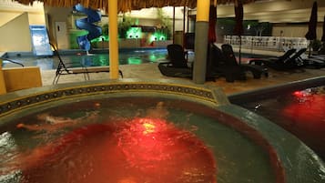 A pool area with a hot tub, lounge chairs, and a water slide.
