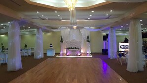 A spacious hall with a wooden floor, white draped curtains, and a central stage with a floral arrangement. - Hotel Miramar Inn (Ciudad Madero)
