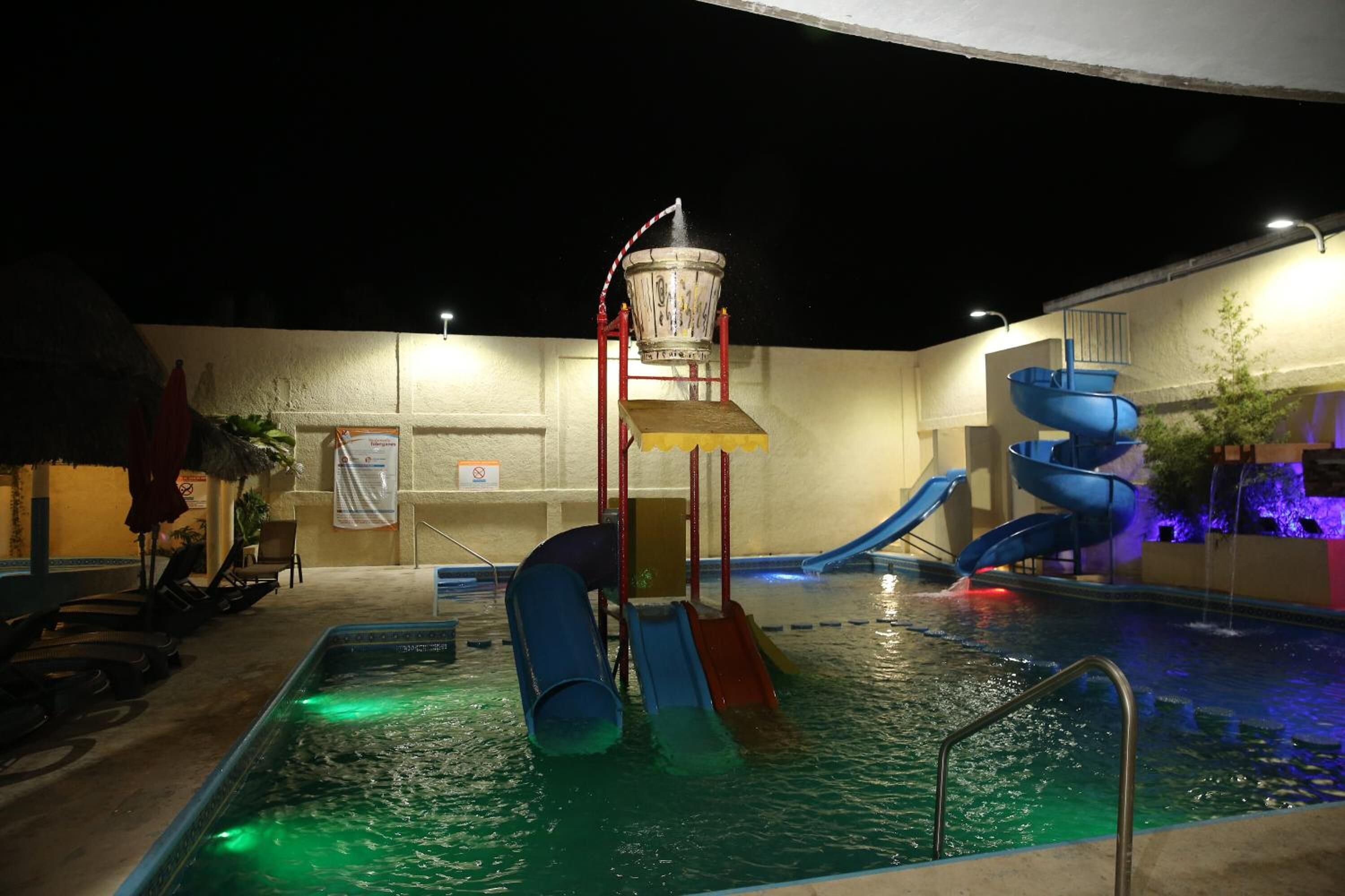 Un área de piscina interior con múltiples toboganes y una fuente de agua.