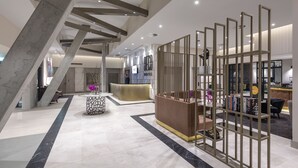 Un moderno vestíbulo de hotel con mostrador de recepción, zona de estar y una escalera.