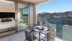 Un balcón moderno con puerta de cristal, un sofá y una mesa de comedor con sillas.