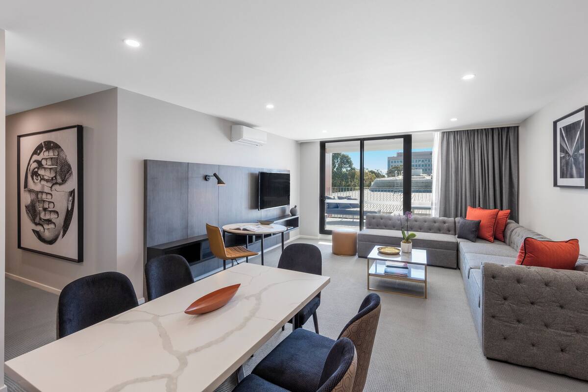 Uma sala de estar moderna com sofá, mesa de centro e área de jantar com cadeiras e mesa.