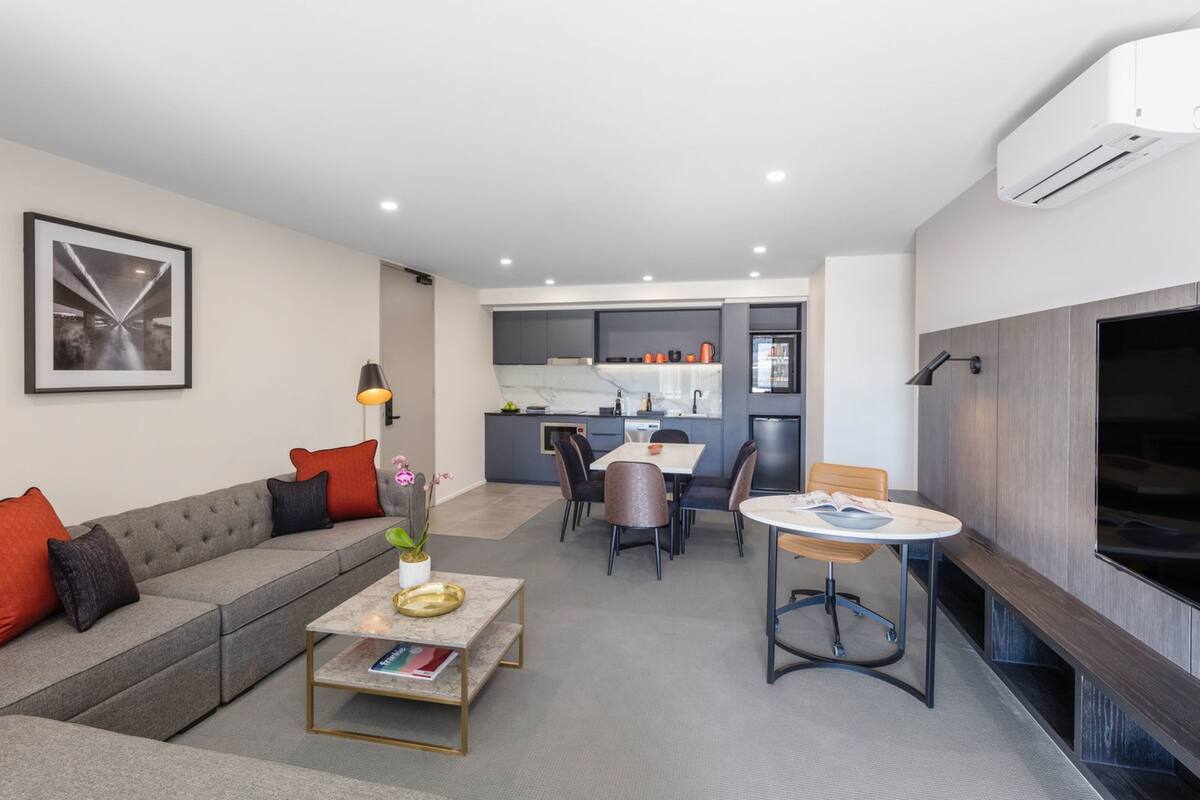 Uma sala de estar moderna com sofá, mesa de centro e área de jantar.
