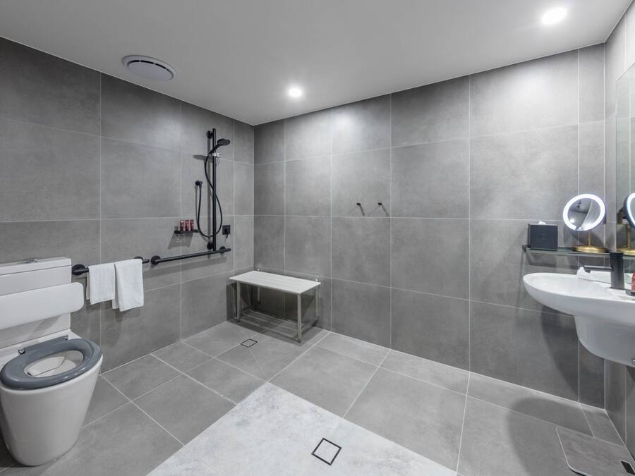 Casa de banho moderna com sanita, bidé, toucador com espelho e zona de duche.