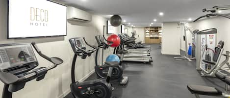 Un gimnasio de hotel con diversos equipos de ejercicio, entre ellos cintas de correr, bicicletas estáticas y máquinas de pesas.