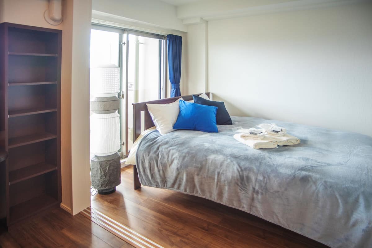 A bedroom with a bed, a wardrobe, and a window with curtains.