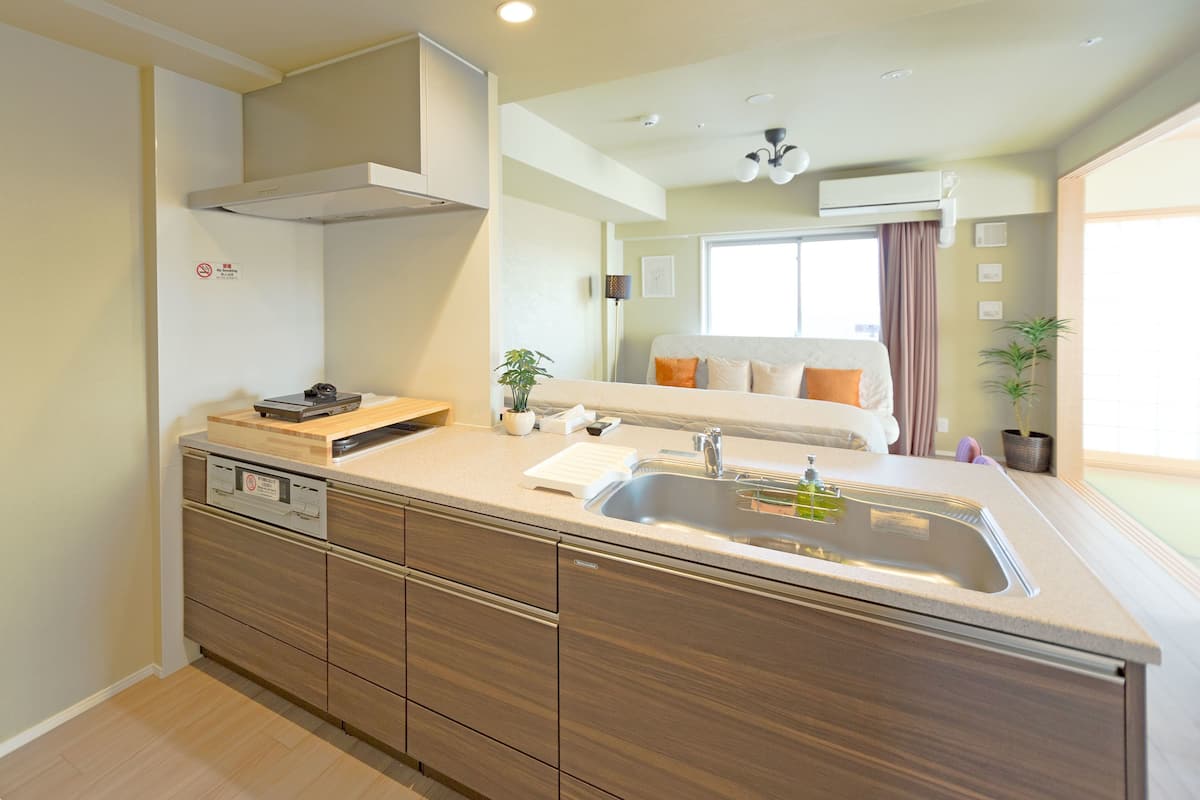 A modern kitchen with a built-in dishwasher, a large sink, and wooden cabinets.