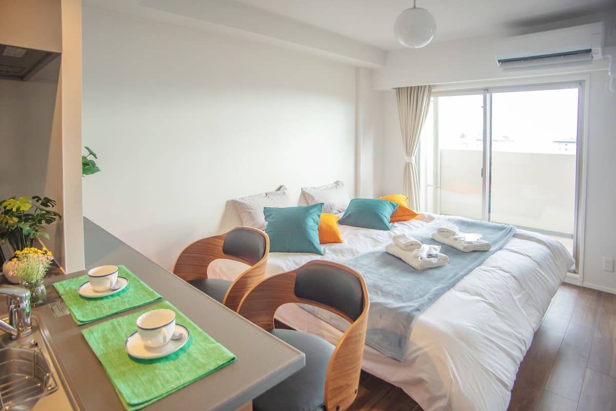A hotel room with a bed, a dining area with chairs and a table, and a window with curtains.