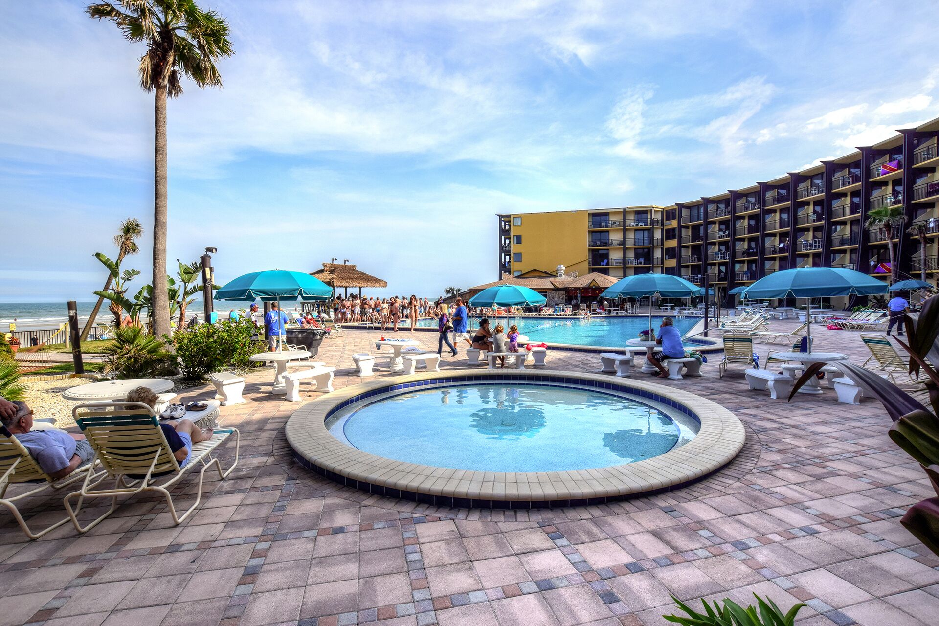 Un espace piscine d’hôtel comprenant un jacuzzi, des chaises longues et des parasols.