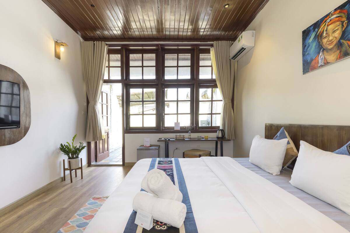 Una habitación de hotel con una cama grande, un escritorio y una ventana con cortinas.