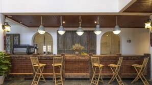 Zona de bar con sillas de madera, una barra y lámparas colgantes.