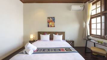 Una habitación de hotel con una cama grande, un cuadro en la pared, un escritorio con hervidor y una ventana con cortinas.