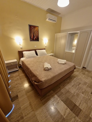 A hotel room with a large bed, two bedside tables, a wardrobe, and a mirror.