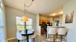 A modern kitchen with wooden cabinets, a central island, and a dining area with a round table and chairs. - University townhome,  available for long-term. (Charlotte)