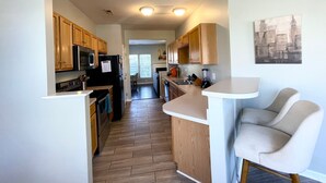 A modern kitchen with wooden cabinets, a black refrigerator, and a white countertop. - University townhome,  available for long-term. (Charlotte)