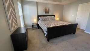A bedroom with a bed, nightstands, a ceiling fan, and a door. - University townhome,  available for long-term. (Charlotte)