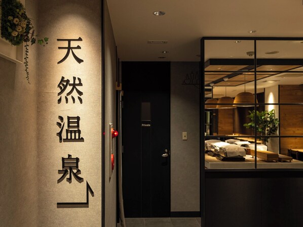 A hotel entrance with a modern design, featuring a reception desk and a private room door.