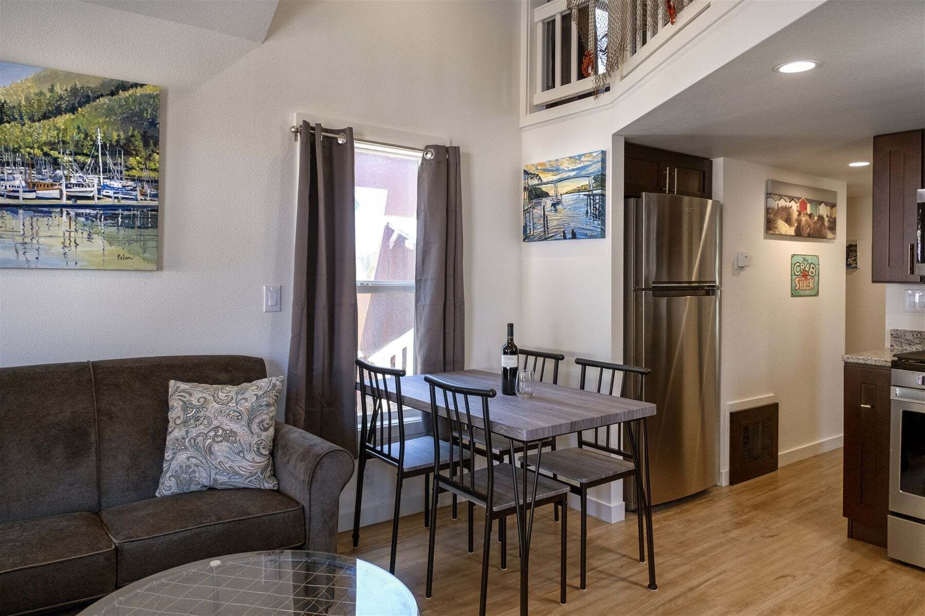 A compact living space with a dining area, kitchenette, and a view of a marina through a window.