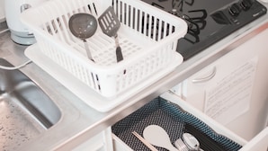 A kitchen with a stove, sink, and white cabinets. There is a white basket with kitchen utensils on the counter. - HATCH NAGAHORI 8th FLOOR (Osaka)