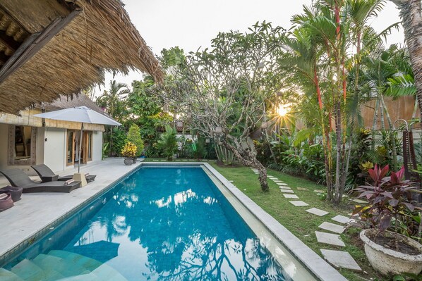 A rectangular swimming pool with a tiled edge, surrounded by a well-maintained lawn and various tropical plants. - Best Location! 3BD Villa, Central Seminyak! - 3Min Walk To Eat Street! W/Pool! (seminyak)