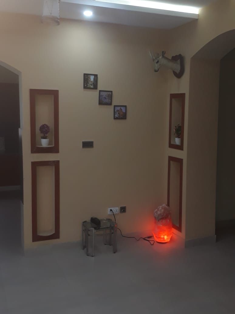 A room with a beige wall, a mounted deer head, and a red light fixture.