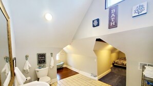 A bathroom with a white sink, a toilet, and a shower area. There is a sign on the wall that says "Bath House." - Experience Indianapolis living close to Lucas Oil Stadium (Indianapolis)