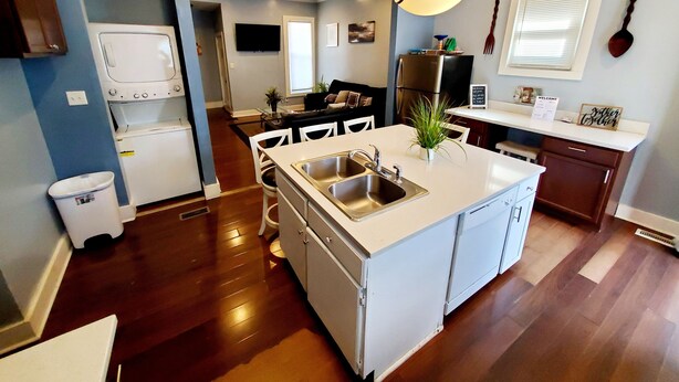 A modern kitchen with a central island, stainless steel appliances, and a dining area with white chairs. - Experience Indianapolis living close to Lucas Oil Stadium (Indianapolis)