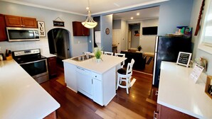A modern kitchen with white countertops, a central island, and wooden cabinets. - Experience Indianapolis living close to Lucas Oil Stadium (Indianapolis)