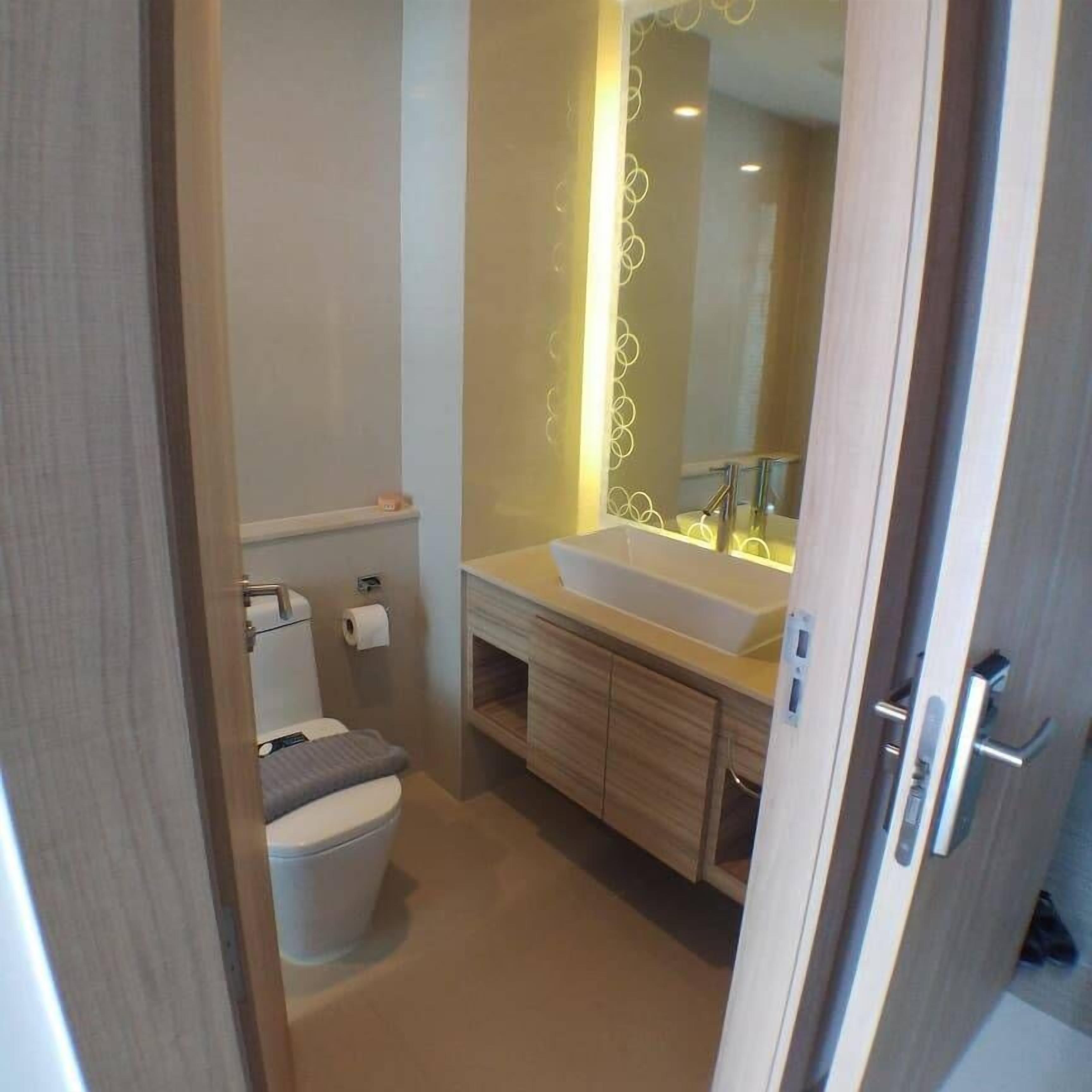 A modern bathroom with a toilet, sink, and mirror.