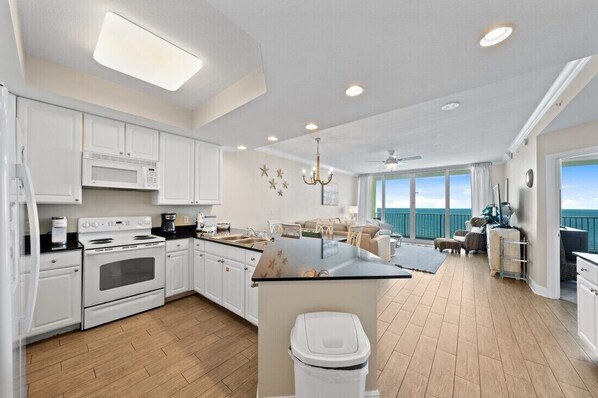 A spacious kitchen with white cabinetry, a central island, and a view of the ocean.