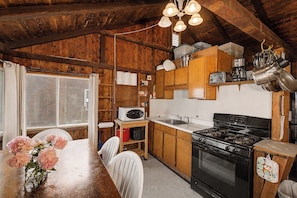 A rustic kitchen with wooden cabinets, a stove, and a microwave.