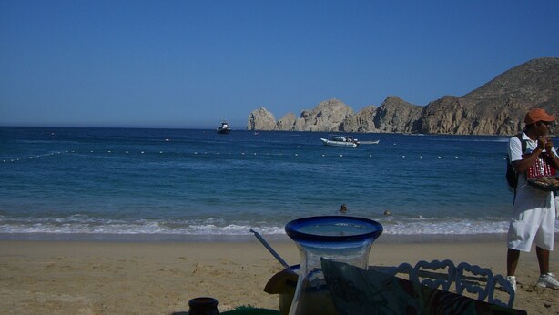 A beach with a clear view of the sea, rocky formations, and a few boats.