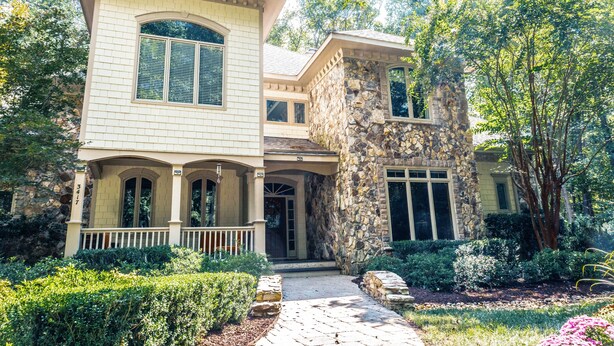 A two-story house with a stone facade, large windows, and a well-maintained garden. - Luxury Secluded Family Retreat (Apex)