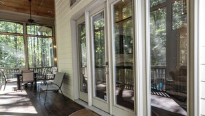 A covered porch with a dining area, large windows, and a wooden ceiling. - Luxury Secluded Family Retreat (Apex)
