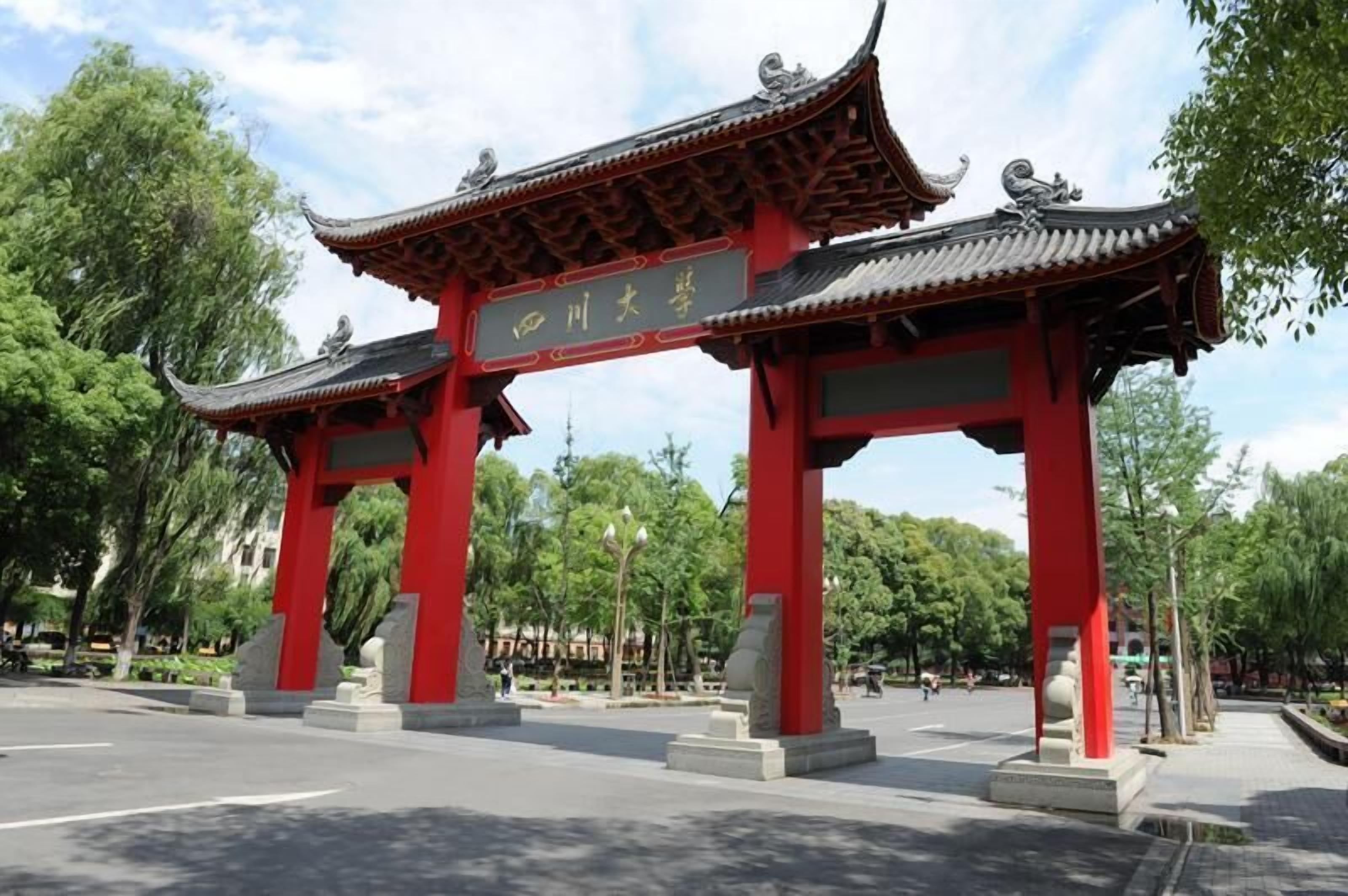 A traditional red gate with Chinese characters, set in a park with trees and a clear sky.