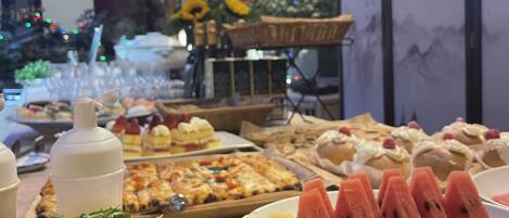 A buffet table with various dishes, including a salad, watermelon slices, and a pizza.