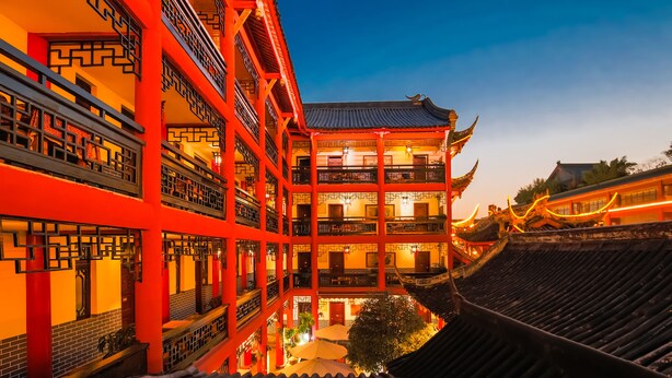 Un edificio tradicional de varios pisos con fachada roja y balcones ornamentales.