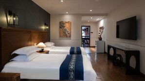 Una habitación de hotel con dos camas, televisión, escritorio y un cuadro en la pared.