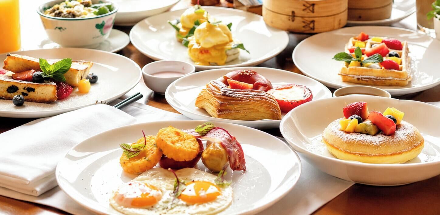 Un bufé de desayuno con diversos platillos, incluyendo panqueques, gofres y pastelería.