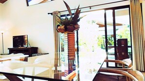 A modern living room with a glass coffee table, a television on a stand, and a potted plant. - Hidden Palms Unit #12 (Nosara)