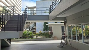 Un bâtiment moderne doté d’un escalier menant à un niveau supérieur, d’un espace extérieur aménagé pour s’asseoir et offrant une vue sur les bâtiments environnants.