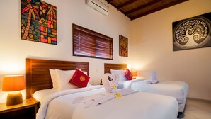 A hotel room with two beds, wooden headboards, and artwork on the walls.